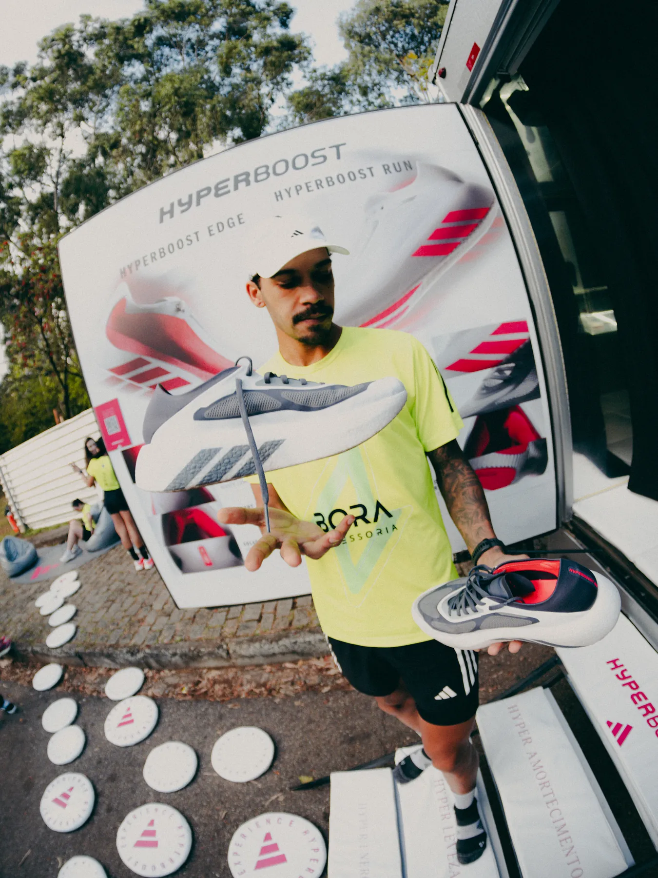 Homem equilibrando tênis Adidas na frente do painel Hyperboost