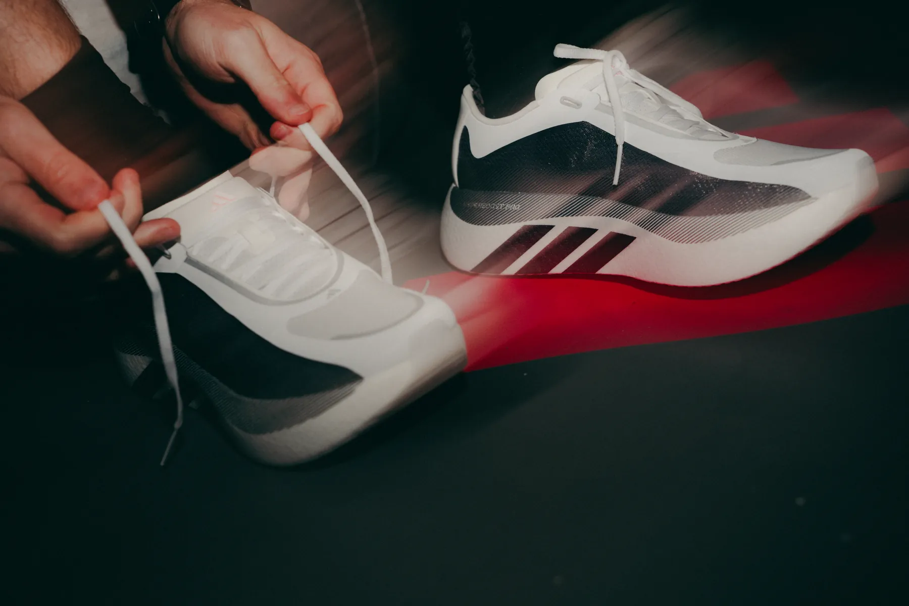 Mãos amarrando o cadarço de um tênis Adidas com efeito de movimento